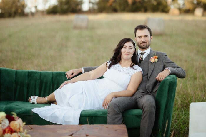 Groom and bride outside on a green couch