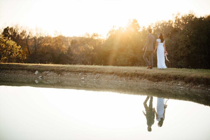 Bride and groom walking around the lake holding hands