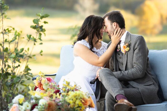 bride and groom sitting down with the bride's hand on grooms face