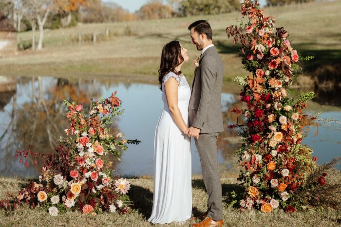 Bride and Groom outside in front of the altar with the lake behind them