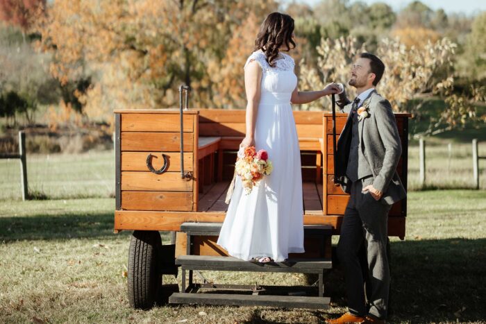 Groom helping his bride down from a wagon